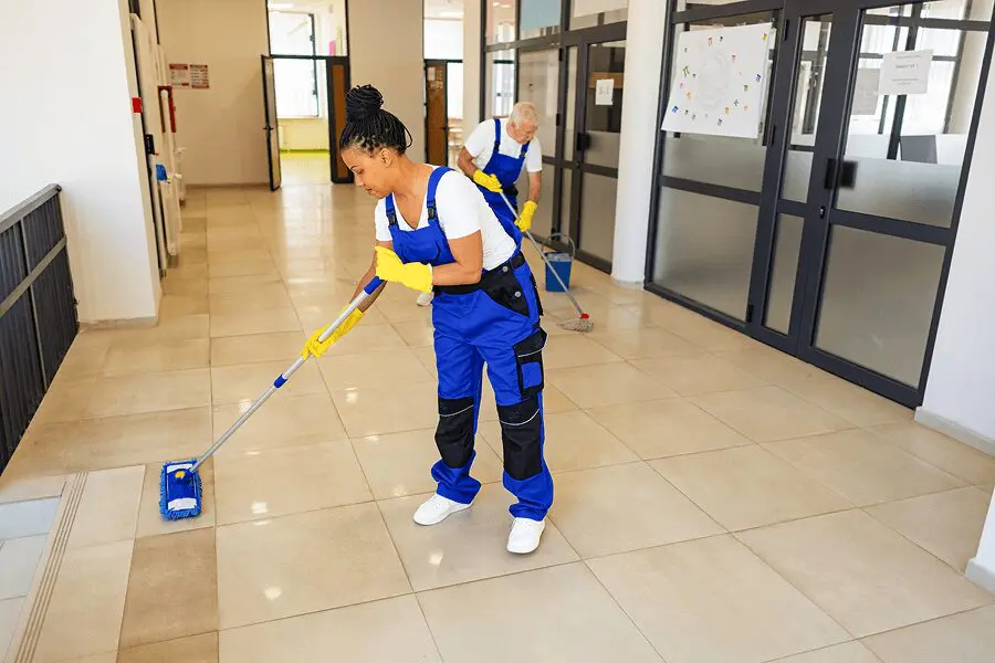 People cleaning a hallway with mops.