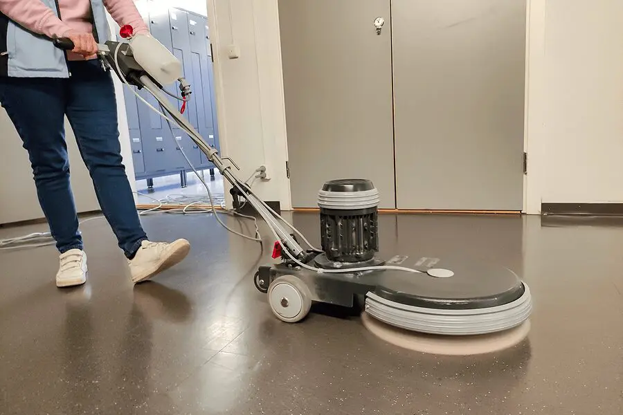 Person using a floor polishing machine indoors.
